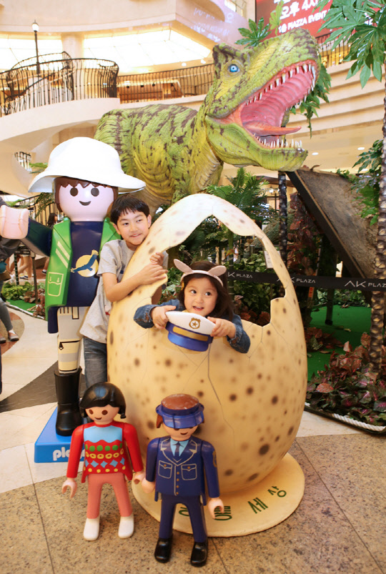 AK플라자는 다음 달 9일까지 '플레이모빌과 함께 떠나는 쇼핑여행'을 테마로 서울 구로본점·수원AK타운점·분당점·평택점·원주점 등 전 점에서 플레이모빌 캐릭터를 활용한 매장을 선보인다. 30일 AK플라자 분당점 1층 피아짜360 광장의 '플레이모빌 & 쥬라기 공룡 전시전'에서 어린이들이 기념 촬영을 하고 있다. <AK플라자 제공>